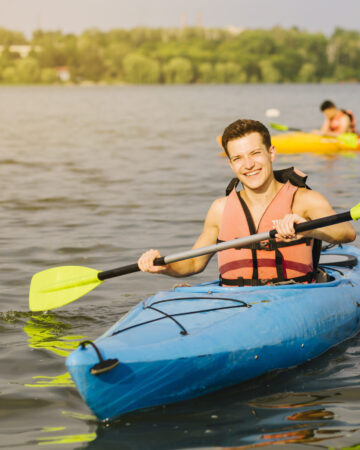 man-using-paddle-while-kayaking-water